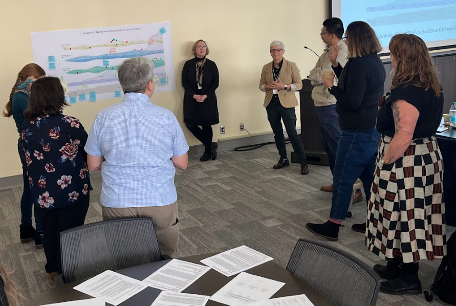BTAA-GIN members stand in front of timeline poster.